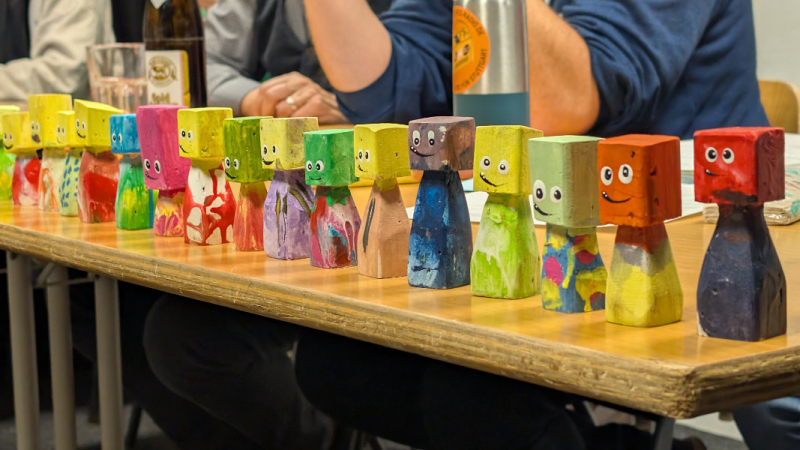 Bunte kleine Holzfiguren mit lustigen Gesichtsausdrücken stehen auf einem Tisch