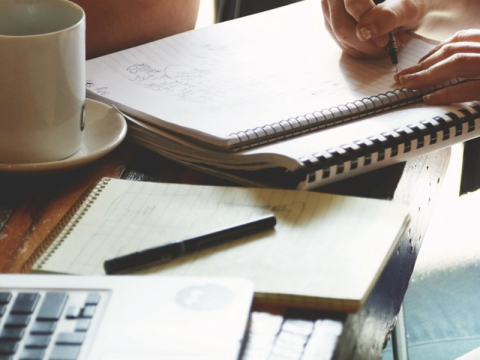 Tisch mit Collegeblock und Händen, eine mit Stift