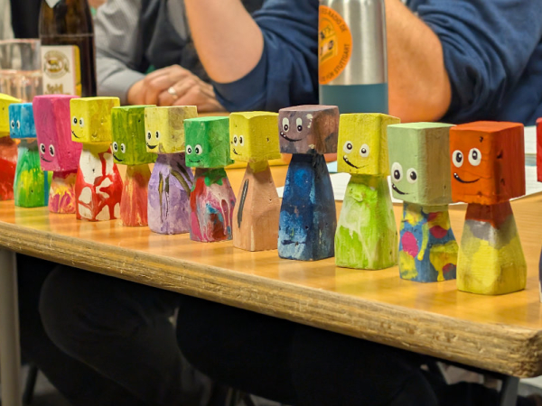 Bunte kleine Holzfiguren mit lustigen Gesichtsausdrücken stehen auf einem Tisch